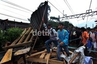 Para penumpang memindahkan kayu-kayu yang digunakan untuk memblokir jalur rel.