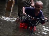 Seluruh ban sepeda terendam, namun bocah ini tetap asyik menggoyes.