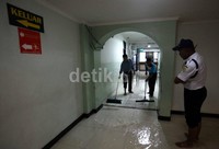 Beberapa petugas membersihkan air yang menggenangi lantai rumah sakit.