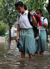 Dua orang siswa harus basah-basahan menembus banjir.