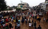 Warga menonton banjir yang menggenangi kawasan Jatinegara.