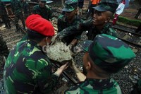 Anggota TNI bahu-membahu mengangkat batu.