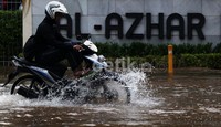 Pengendara melintasi banjir di sekolah Internasional Islam Al-Azhar Kelapa Gading.