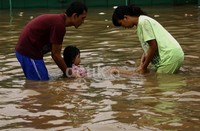 Suami istri mengajar anaknya berenang di lokasi banjir. Ramses/detikFoto.