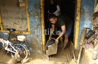 Warga membuang sisa lumpur yang terbawa banjir.