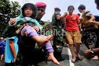 Seorang bocah dibantu anggota Marinir di kawasan banjir. Banjir Pluit belum surut di hari kedua.