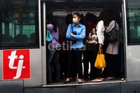 Para penumpang menunggu di atas bus yang mogok.