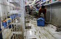 Sejumlah karyawan minimarket membersihkan tempat kerja mereka yang porak poranda akibat banjir.