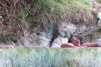 Seorang wisatawan menikmati enaknya berendam air panas. Kalau ingin berendam air panas sambil berekreasi, Tirta Sanita bisa menjadi pilihan wisatawan. Tapi, jika naluri petualangan Anda cukup tinggi, naik saja ke puncak Gunung Hitam untuk kolam rendam biasa, namun dengan pemandangan luar biasa (Fitraya/detikTravel)
