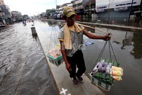 Seorang pedagang tetap berjualan meski kawasan tersebut masih tergenang banjir.