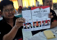 Panitia TPS Kel. Sinrijala memperlihatkan surat suara yang bergambar tiga pasangan cagub dan cawagub.