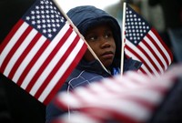 Seorang bocah menghadiri upacara pelantikan dengan membawa bendera AS. Reuters/Eric Thayer.