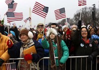 Warga menyaksikan pelantikan sambil mengibarkan bendera AS. Reuters/Shannon Stapleton.