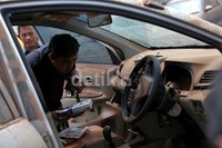 Seorang pemilik memeriksa berkas-berkas yang tertinggal di dalam mobil.