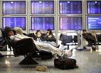 Sejumlah penumpang menunggu keberangkatan dengan tiduran di ruang tunggu Bandara Frankfurt. Reuters/Lisi Niesner.