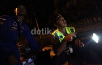 Polisi mengecek rumah-rumah warga menggunakan senter.