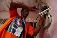 Petugas PLN melakukan pergantian KWh meter di rumah korban banjir di Cililitan.