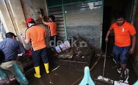 Tampak warga membersihkan rumahnya yang masih penuh lumpur akibat banjir.