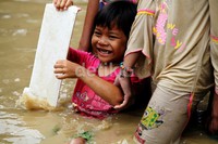 Seorang anak asyik bermain banjir di sekitar rumahnya.