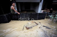 Seorang warga bertahan dengan duduk di atas pagar rumahnya.