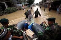 Perahu karet TNI menyusuri jalanan yang terendam banjir untuk mengevakuasi warga.