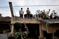 TNI memberikan bantuan makanan kepada warga yang bertahan di atap rumah.