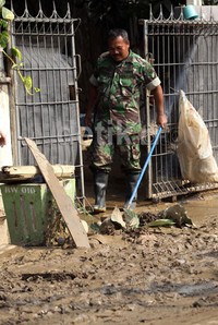 Anggota TNI membersihkan lumpur sisa banjir.