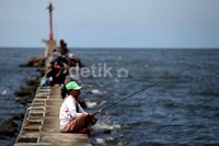 Sejumlah warga memancing ikan di tanggul pemecah ombak kawasan Pelabuhan Muara Baru, Senin (4/2/2013).