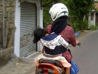 Seorang ibu yang membonceng anaknya dengan cara melilitkan sebuah kain agar anak tidak jatuh. Foto ini diambil di Cilebut Bogor. Ini kreatif atau blunder? (Amadhan Takwir) 