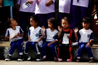 Beberapa anak melambaikan tangan ke arah arak-arakan kendaraan hias.