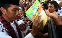 Jokowi langsung membagikan buku kepada anak-anak yang mengerumuninya.
