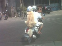 Anjing itu duduk manis menjadi boncenger dengan mengenakan helm berwarna putih, sambil mengamati jalanan. (Foto Hartawan Sugijo)