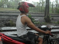 Mungkin untuk berlindung dari hujan, pengendara motor ini mengubah spakbornya menjadi helm. (Foto Ach. Hafi Ansori).