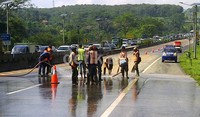 Petugas menyemprotkan air untuk membersihkan jalan dari tanah yang tersisa.
