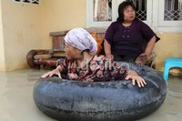 Seorang nenek bermain air dengan ban bekas.