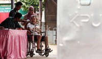 Warga Kelurahan Jaka Sampurna, Bekasi Barat, dengan menggunakan kursi roda ditemani sang istri, mendatangi bilik lokasi pencoblosan di TPS 24.