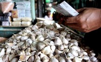 Seorang pedagang menjual bawang putih di Pasar Induk Kramatjati, Jakarta Timur.
