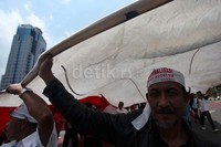 Para pendemo membentangkan bendera merah putih raksasa yang dibawanya.