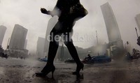 Pejalan kaki melintas di kawasan Thamrin yang diguyur hujan deras.
