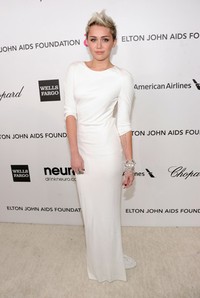 Dress putih panjang yang dikenakan Miley terlihat sederhana jika dilihat dari depan. Jamie McCarthy/Getty Images for EJAF.
