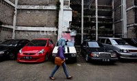 Hanya sedikit masyarakat berpenghasilan rendah yang menikmati rusun ini. Seorang warga melintas di depan mobil-mobil milik penghuni rusun yang terparkir di depan rusun bidaracina, Jakarta.