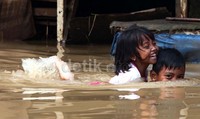 Anak-anak bermain di saat banjir.