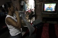Seorang warga menonton televisi yang memberitakan soal meninggalnya Hugo Chavez. Reuters/Inti Ocon.