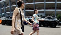 Dua wanita melintas didepan kendaraan rantis Anoa 6X6, saat simulasi Paspamres di sekitar wilayah Stadion Utama GBK Senayan, Jakarta.