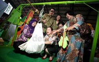     Veronica Tan ikut membantu menimbang berat badan salah satu balita.