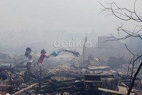 Warga berusaha mendinginkan bekas kebakaran yang masih panas terasa. Disela-sela kebakaran tersebut sempat terjadi  insiden pemukulan warga ke wartawan yang sedang meliput.