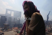Seorang warga meratapi rumahnya yang hangus terbakar.
