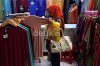 Seorang pengujung melihat pakaian yang akan dibelinya.