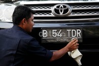 Seorang sopir, tengah membersihkan pelat nomor mobilnya. Polri kembali memberi peringatan kepada para pengguna kendaraan, untuk tidak memodifikasi atau mengutak-atik plat nomor.