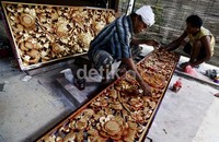     Dua orang seniman ukir Bali sedang menyelesaikan pesanan kayu ukir untuk hiasan rumah.